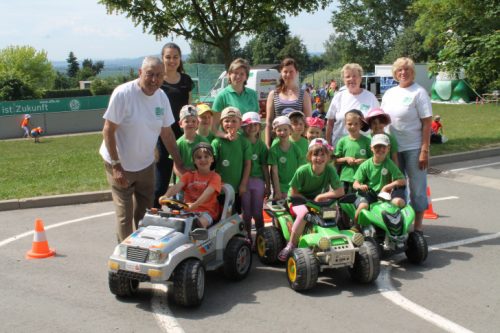 Kinder des Fremdsprachenkindergartens „Little Food“ in Wüstenbrand mit ihren Erzieherinnen und Hofmann von der Kreisverkehrswacht beim Probieren der Elektrofahrzeuge. Foto: Uwe Wolf