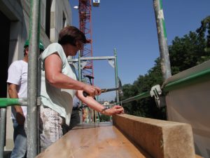 GGZ-Geschäftsführerin schlägt zum Richtfest den Nagel auf ein Stück Holz. Eine Dachkonstruktion im klassischen Sinne gibt es nicht. Foto: Alice Jagals