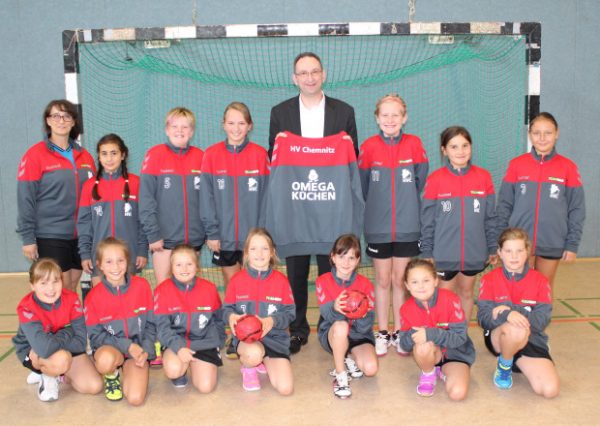 Die Trainerin (h.l.) und die Mädchen der E-Jugend des Handballverein Chemnitz freuen sich riesig über die gesponserten Jacken von Rajko Müller, dem Inhaber von Omega Küchen (h.m.). Foto: Nicole Neubert